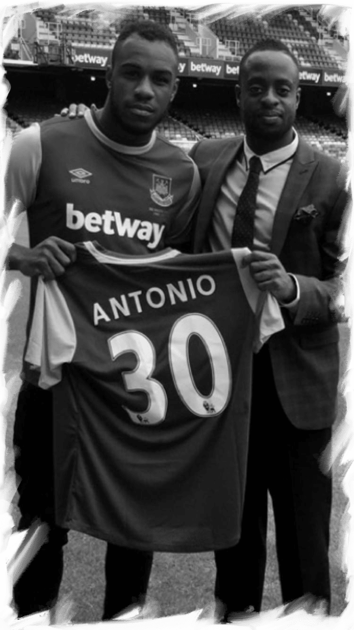 A man holding up a soccer jersey with another man standing next to him.