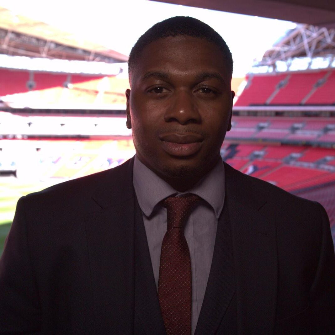 A man in suit and tie standing next to a stadium.