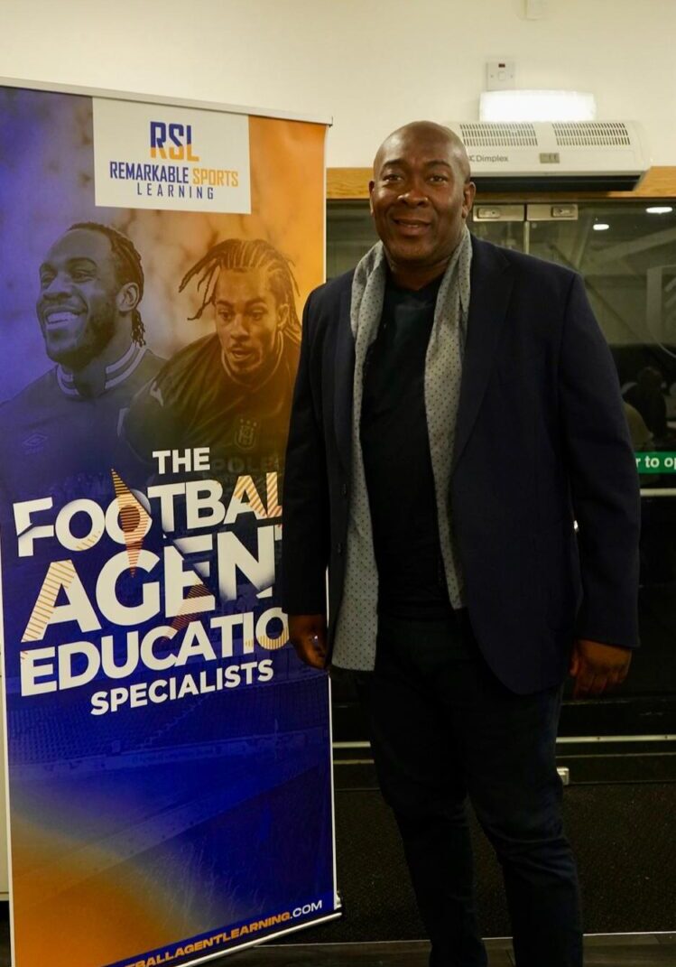 Nigel James w RSL Banner A man standing next to a banner that says football agent education specialists.