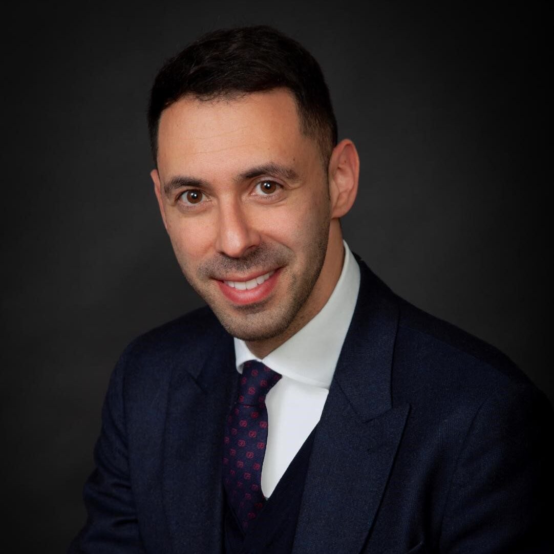 A man in a suit and tie smiling for the camera.